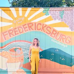 a woman standing in front of a painted wall with the words friederricksburg on it