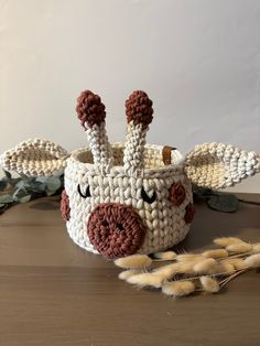 a crocheted basket with an animal's face on it, sitting on a table