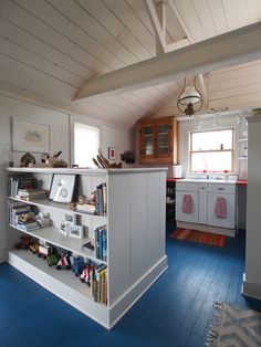 a kitchen with blue flooring and white cabinetry in the center is filled with books