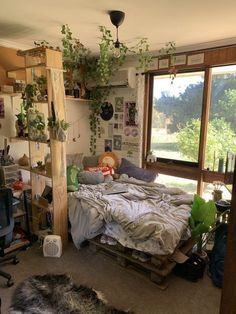 an unmade bed sitting next to a window in a room with lots of plants