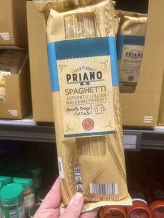 a person holding up a bag of pasta in a grocery store aisle with other items on the shelves behind them