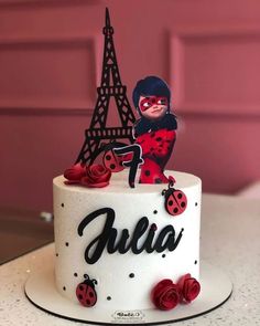 a white cake with ladybug decorations and the eiffel tower in the background