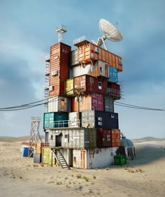 a large stack of shipping containers sitting on top of a sandy beach next to a satellite dish