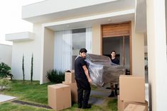 two men unloading boxes in front of a house