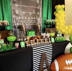 a football themed party with green and gold decorations, balloons, and desserts on a table