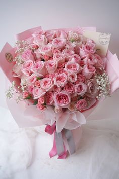 a bouquet of pink roses with baby's breath in the center is on display