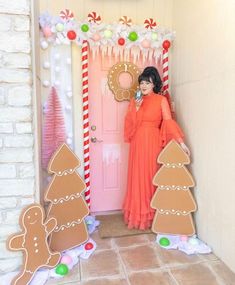 a woman standing in front of a door decorated with gingerbreads and christmas decorations