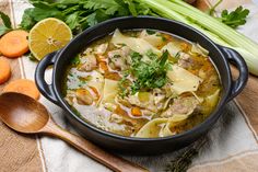 a bowl of chicken noodle soup with carrots, celery and parsley