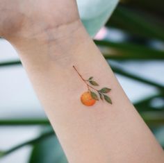 an orange tattoo on the arm of a woman's left arm, with leaves growing from it