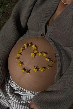 a pregnant woman with yellow flowers on her stomach is shown in the shape of a smiley face