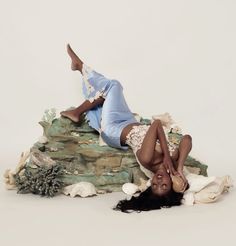 a woman laying on top of a pile of seashells