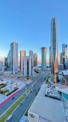 an aerial view of a city with skyscrapers and cars driving on the road in front of it