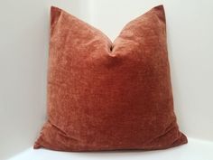 an orange pillow sitting on top of a white table