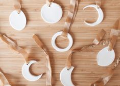 some white ornaments are hanging on a wooden table with ribbon around them and tied together