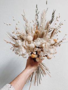 a person holding a bunch of flowers in their hand with white and brown colors on it