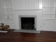 an empty living room with a fireplace and shelves