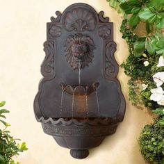 an outdoor wall fountain with lion head design