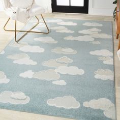 a blue rug with clouds on it in front of a chair and door leading into a living room