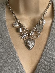 This statement necklace features seven charms: stainless steel bee shield in center, rodium plated CZ protection Talisman charm, mother of pearl CZ heart, CZ horn, stainless steel padlock, Northstar and button pearl CZ clover. These charms hang on a stainless steel sturdy non tarnish chain. Adjustable length including the extension is approximately 17-19 inches. Stainless steel lobster clasp. 🎁All orders are shipped in a box. Gift messages are attached to the box. Silver Pendant Charm Necklace With Removable Charms, Silver Sterling Charm Necklace With Detachable Pendant, Silver Charm Necklace With Detachable Pendant, Silver Pendant Charm Necklace With Vintage Charm, Silver Sterling Charm Necklace With Removable Charms, Silver Pendant Necklace With Vintage Charm, Silver Jewelry With Removable Heart Pendant Charms, Silver Heart Necklace With Removable Charms, Protection Talisman