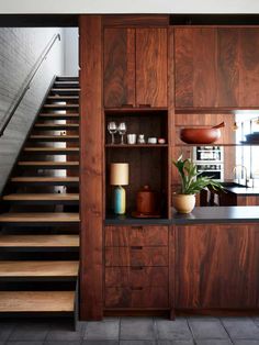 a kitchen with wooden cabinets and stairs leading up to the upper floor