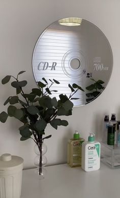 a white counter top topped with a vase filled with flowers next to a cd disc