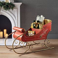 a red sleigh filled with gifts next to a fireplace