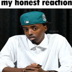 a man wearing a green hat sitting in front of a black curtain with the words my honest reaction on it