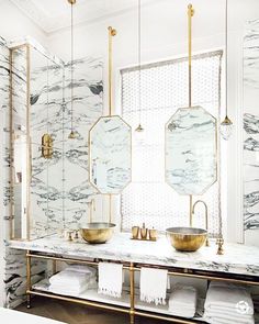 a bathroom with marble counter tops and gold fixtures on the wall, along with two sinks