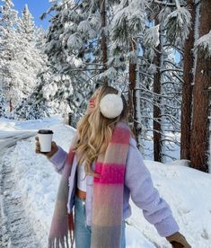 a woman standing in the snow holding a cup of coffee