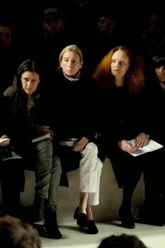 three women sitting next to each other at a fashion show