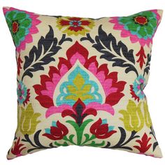 an embroidered pillow with colorful flowers and leaves on the front, sitting on a white surface