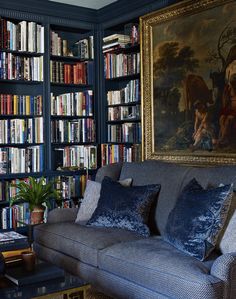 a living room with bookshelves and couches in front of a painting on the wall