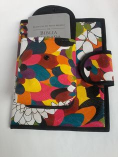 a colorful book with a black ring on the front and bottom cover that has flowers all over it