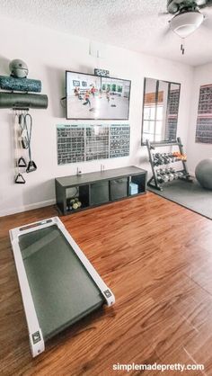 an exercise room with treadmills, yoga mat and other equipment on the wall