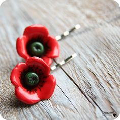 two red flowers with green centers sitting on top of a wooden table