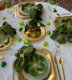 the table is set with gold and green plates, napkins, and silverware