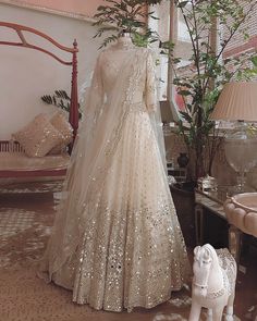 a wedding dress on display in a room with a horse figurine next to it