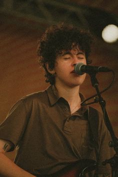 a young man singing into a microphone while playing the guitar