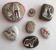 four painted rocks with animals and people on them