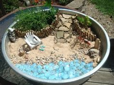 an outdoor garden with rocks, gravel and chairs in the middle is displayed on a table