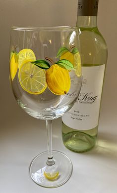 a wine glass with lemons on it next to a bottle