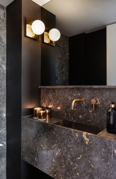 a bathroom with black marble counter tops and gold faucets on the sink area