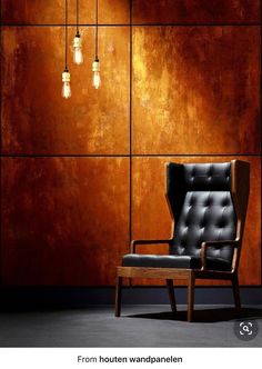 a black chair sitting in front of a wall with lights hanging from it's sides