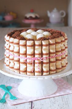 there is a cake with bananas on it and pink ribbon around the edges, sitting on a white plate