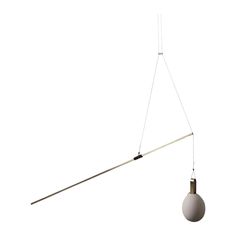 a white light hanging from the ceiling with a long cord attached to it and an object in front of it