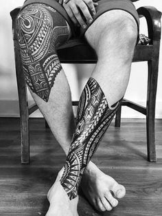 a man sitting on top of a chair with his leg covered in tattoo designs and tattoos