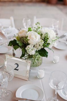 a vase filled with flowers sitting on top of a table covered in white linens