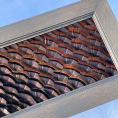 a wooden frame with an abstract pattern in the center and sky behind it on a sunny day