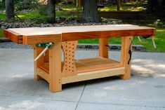 a wooden workbench sitting on top of a cement floor in front of trees