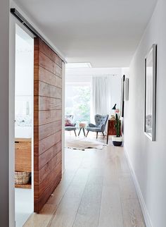 an open door leading to a living room with white walls and wood floors, along with two chairs